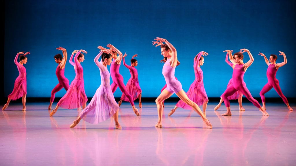 Dancers wearing shades of pink raise their arms in "Symphonic Dances" by Rex Wheeler.\